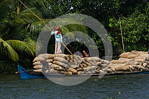 Allepey, Kerala, India Ã¢â¬â March 31, 2015: Indian man transport dwell with rice for boats. backwaters canoe in state